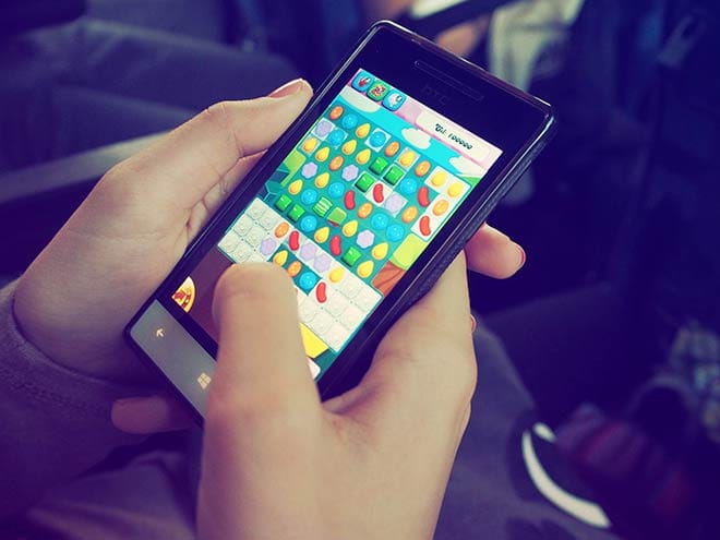 In-Game Purchases: Person playing Candy Crush Saga on a phone.